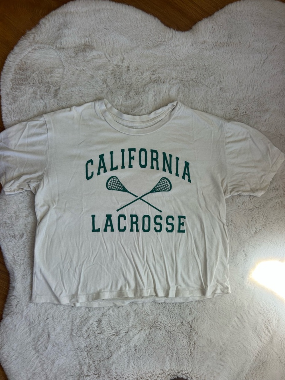 Rebellious One White Tee with green “California Lacrosse” lettering